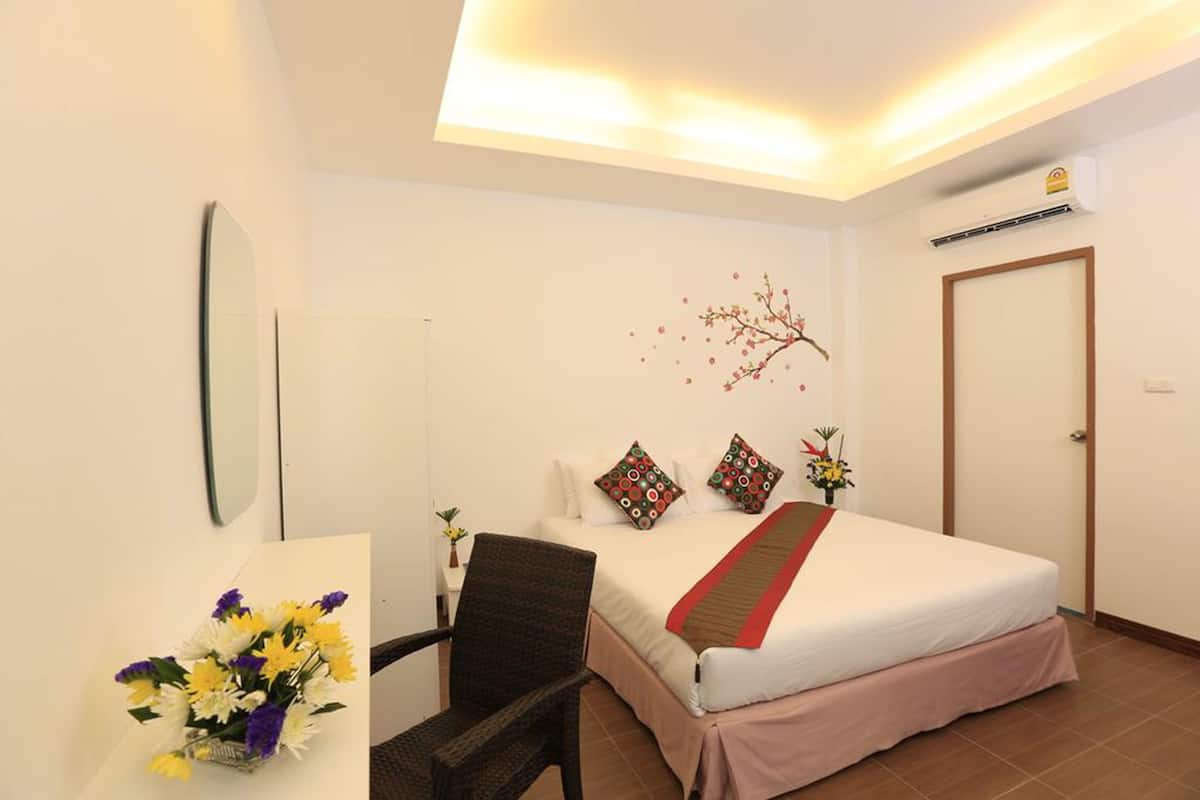 Quarto de hotel com cama, uma cadeira, escrivaninha e decoração na parede.