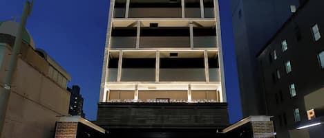 Un edificio a più piani dal design moderno, con una serie di balconi e un'area d'ingresso coperta.