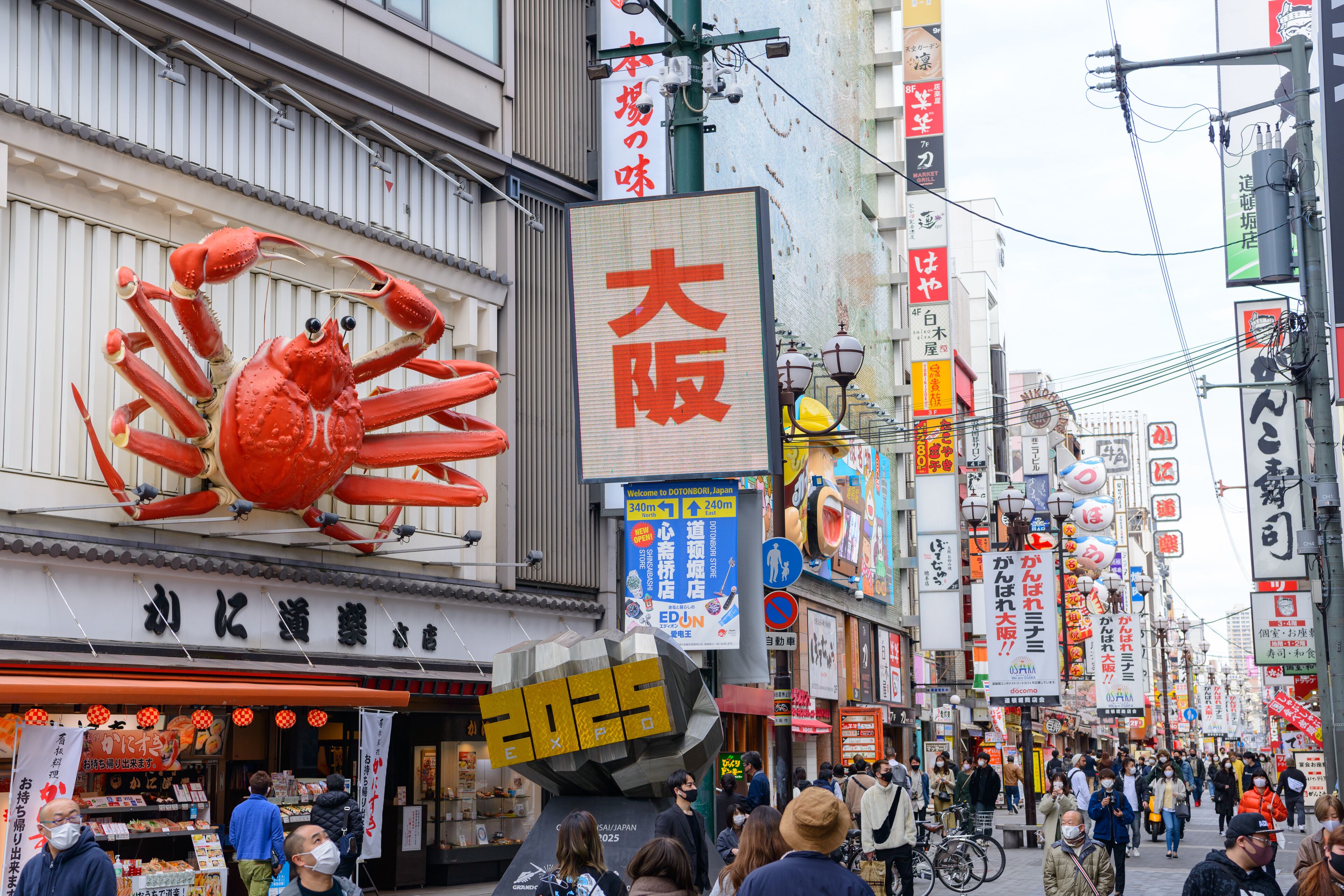 Une rue animée, avec une grande publicité représentant un crabe et divers panneaux en langue étrangère.