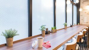 Una larga mesa de madera con plantas en macetas, una taza de café y una servilleta.