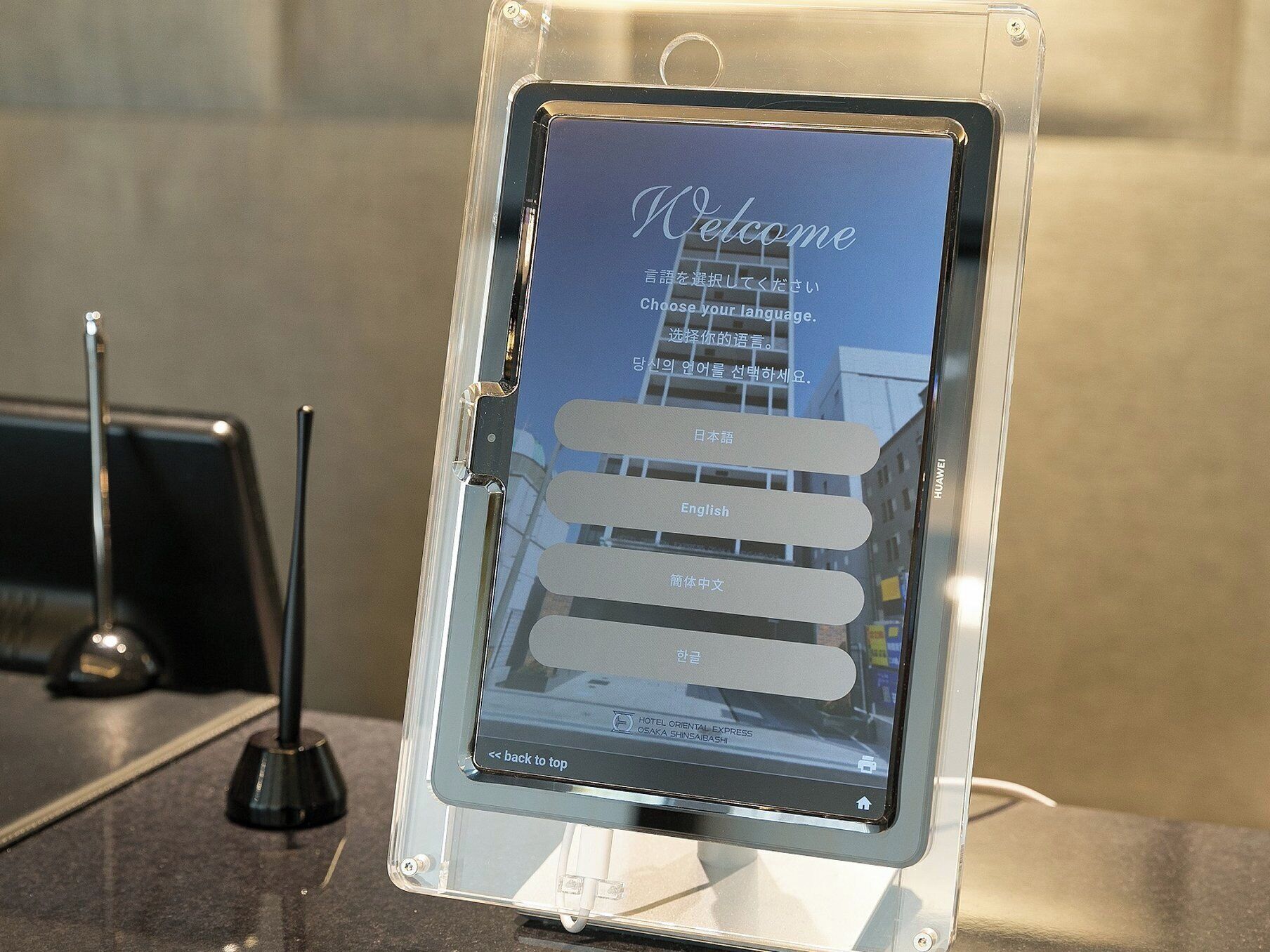 Ein digitales Display mit einer Willkommensnachricht und Optionen zur Sprachauswahl.