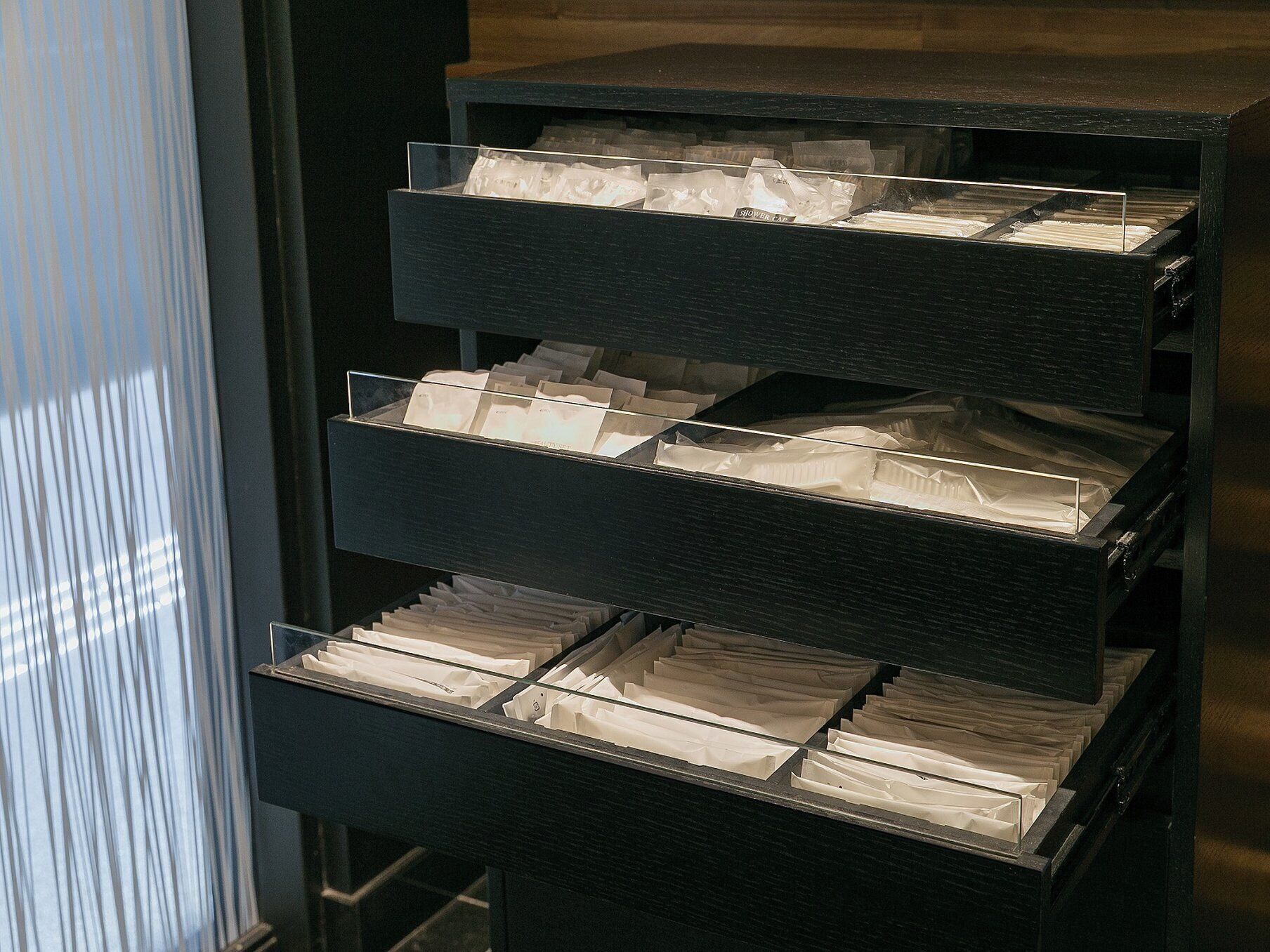 A black filing cabinet with multiple drawers, each containing white folders.