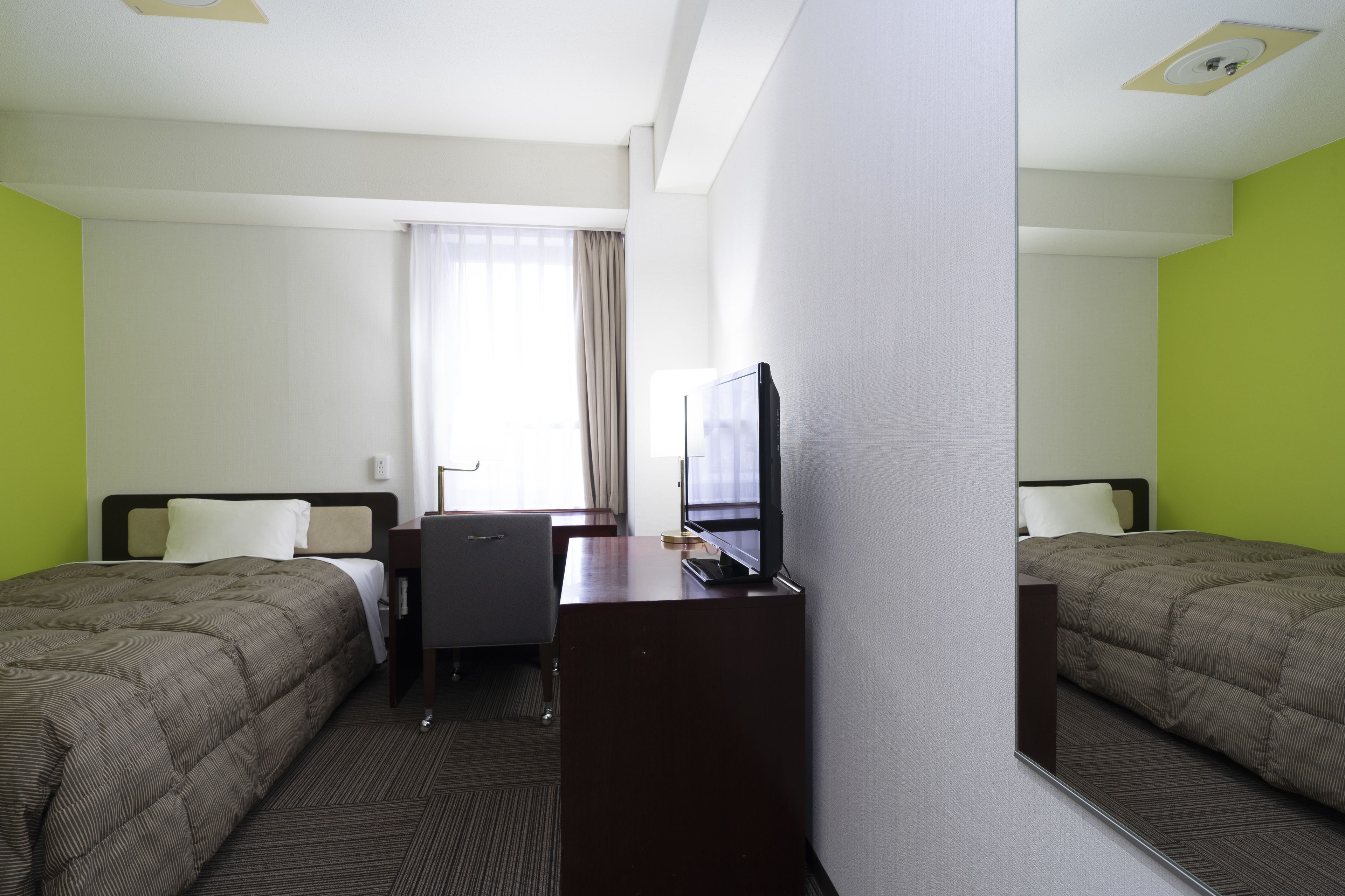 Une chambre d’hôtel avec deux lits, un bureau, une télévision et une fenêtre avec des rideaux.