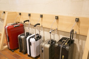A row of suitcases on a wall-mounted rack. - Hotel S-Plus Hiroshima Peace Park (Hiroshima)