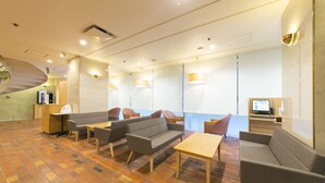 Een moderne lobby met een spiltrap, zitgedeeltes en een receptiebalie.