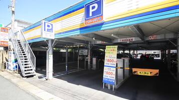A parking garage entrance with a blue and yellow striped awning, a parking sign, and a staircase leading to an underground parking area.