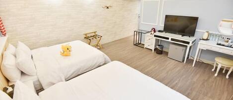 A hotel room with two beds, a desk with a TV, and a small seating area.