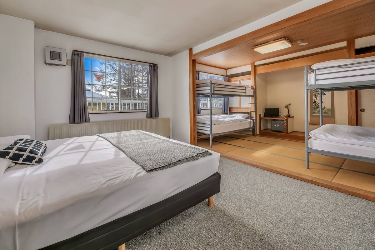 A modern hotel room with a single bed, a desk, and a bunk bed.