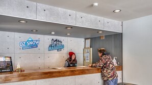Un comptoir d’accueil en bois, un petit sapin de Noël et une enseigne indiquant « Hôtel Madarao ».