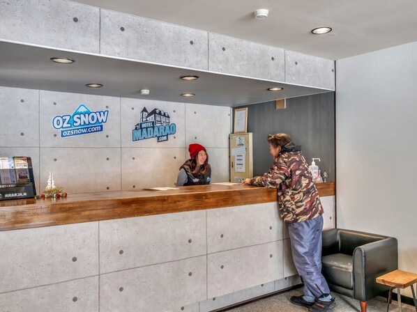 A hotel reception desk with a wooden counter, a small Christmas tree, and a sign for Hotel Madarao. - Hotel Madarao (Myoko)