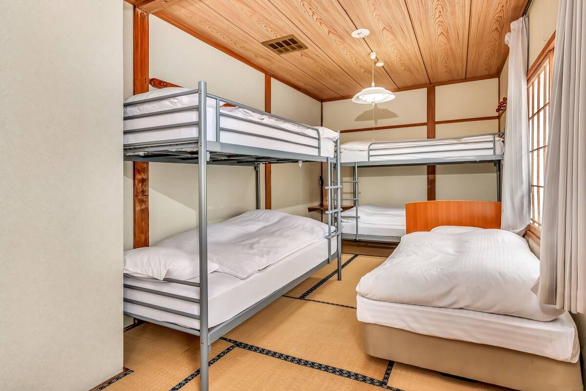 A bunk room with three bunk beds, a wooden ceiling, and a single bed.