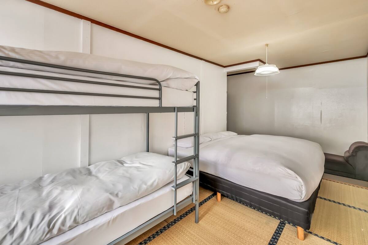 A bunk bed room with a desk and a hanging light fixture.