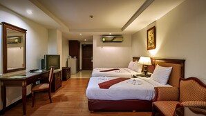 A hotel room with two beds, a desk, a chair, a television, and a mirror. - Nana Hiso Hotel (Bangkok)