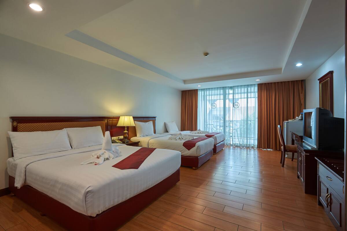 A hotel room with two beds, a television, and a desk.