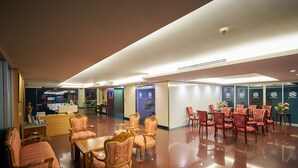 A spacious hotel lobby with a mix of seating areas, including a dining section with tables and chairs, and a reception area with a counter and decorative items. - Nana Hiso Hotel (Bangkok)