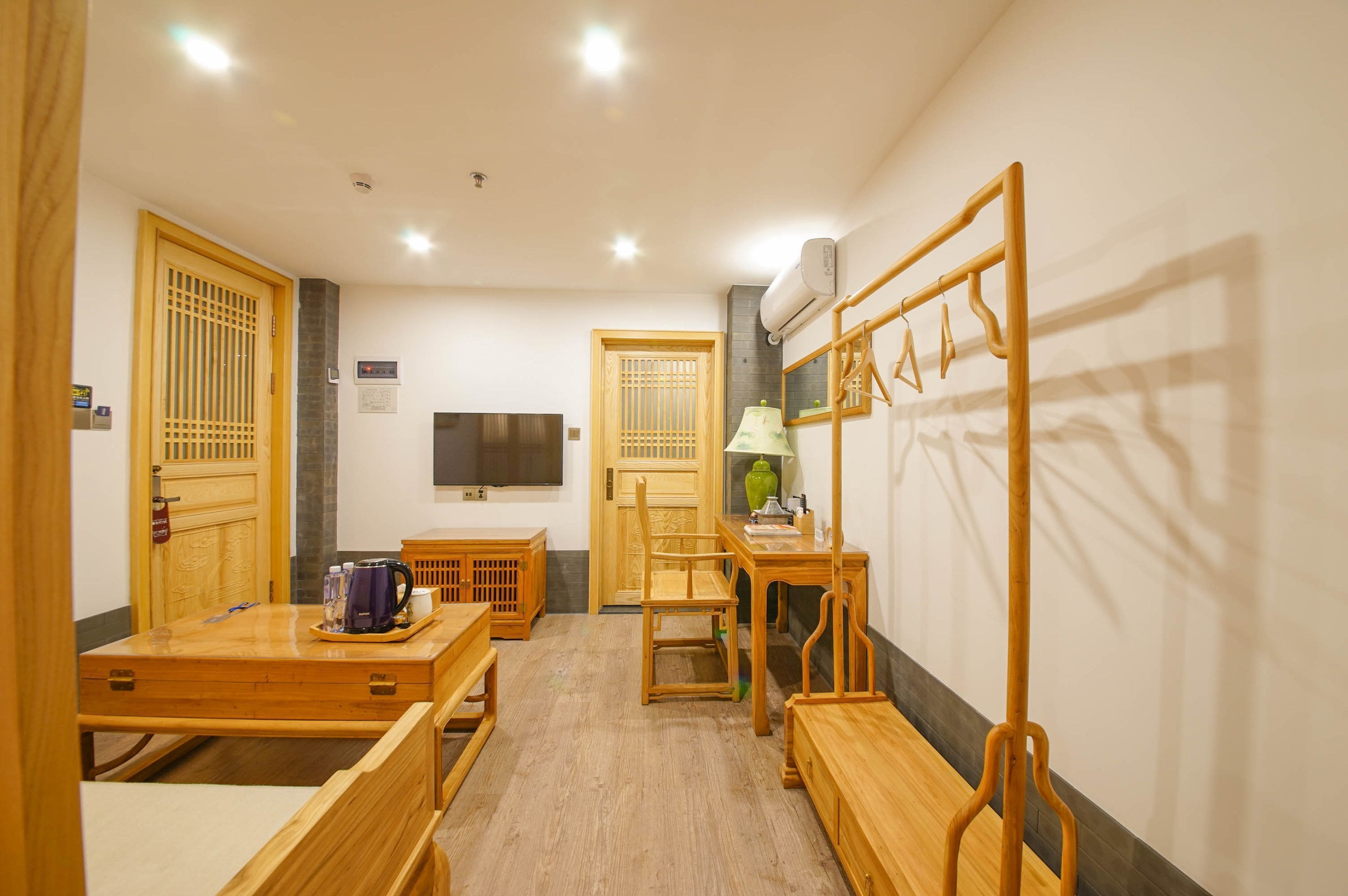Habitació d'hotel amb taula de fusta, cadires, televisió i armari.