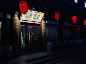 A traditional Chinese building with a signboard, red lanterns, and wooden pillars with Chinese characters.