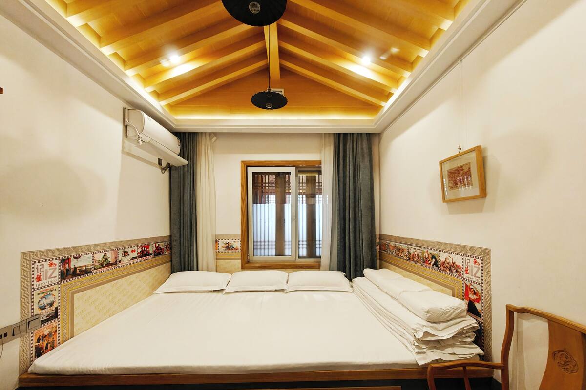 Habitación de hotel con una cama grande, cabecera de madera y techo con vigas de madera.