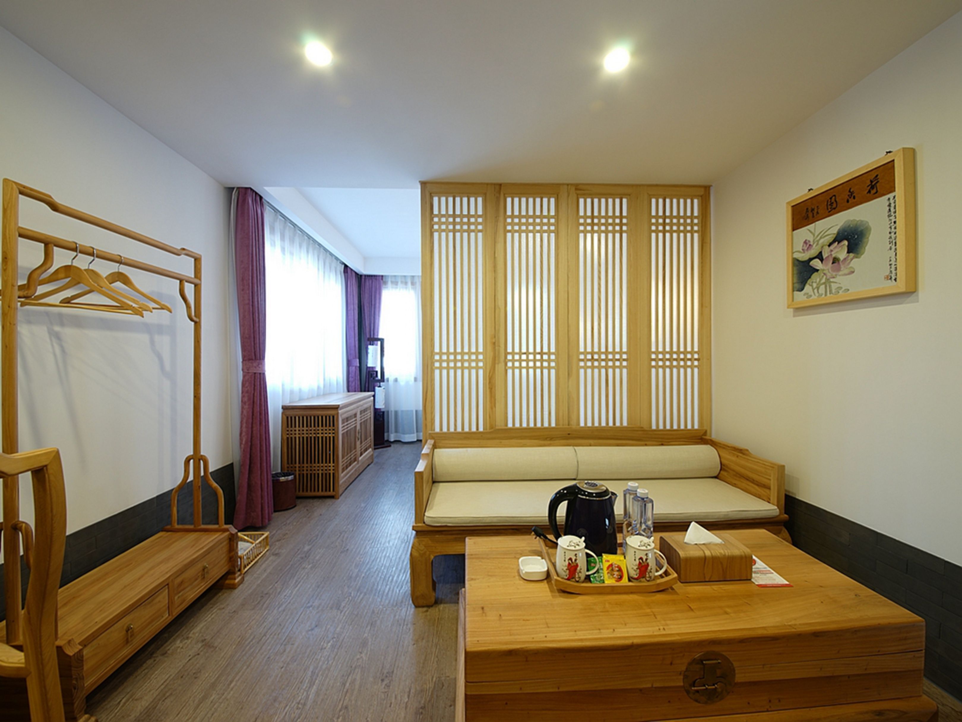 Una habitación con un banco de madera, una mesa de madera con una bandeja de objetos, un armario de madera y una puerta corredera con vistas.