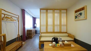 Una habitación con un banco de madera, una mesa de madera con una bandeja de objetos, un armario de madera y una puerta corredera con vistas.