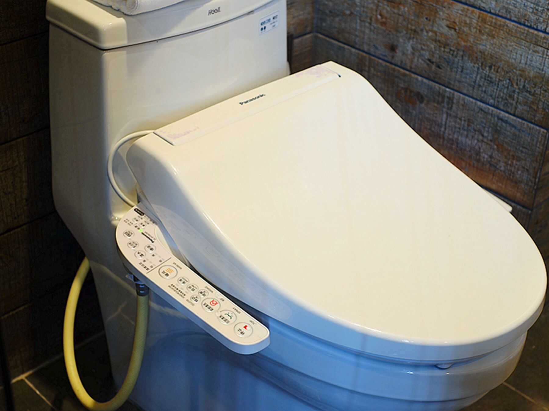 Een toilet met een bedieningspaneel en een douchetoilet.