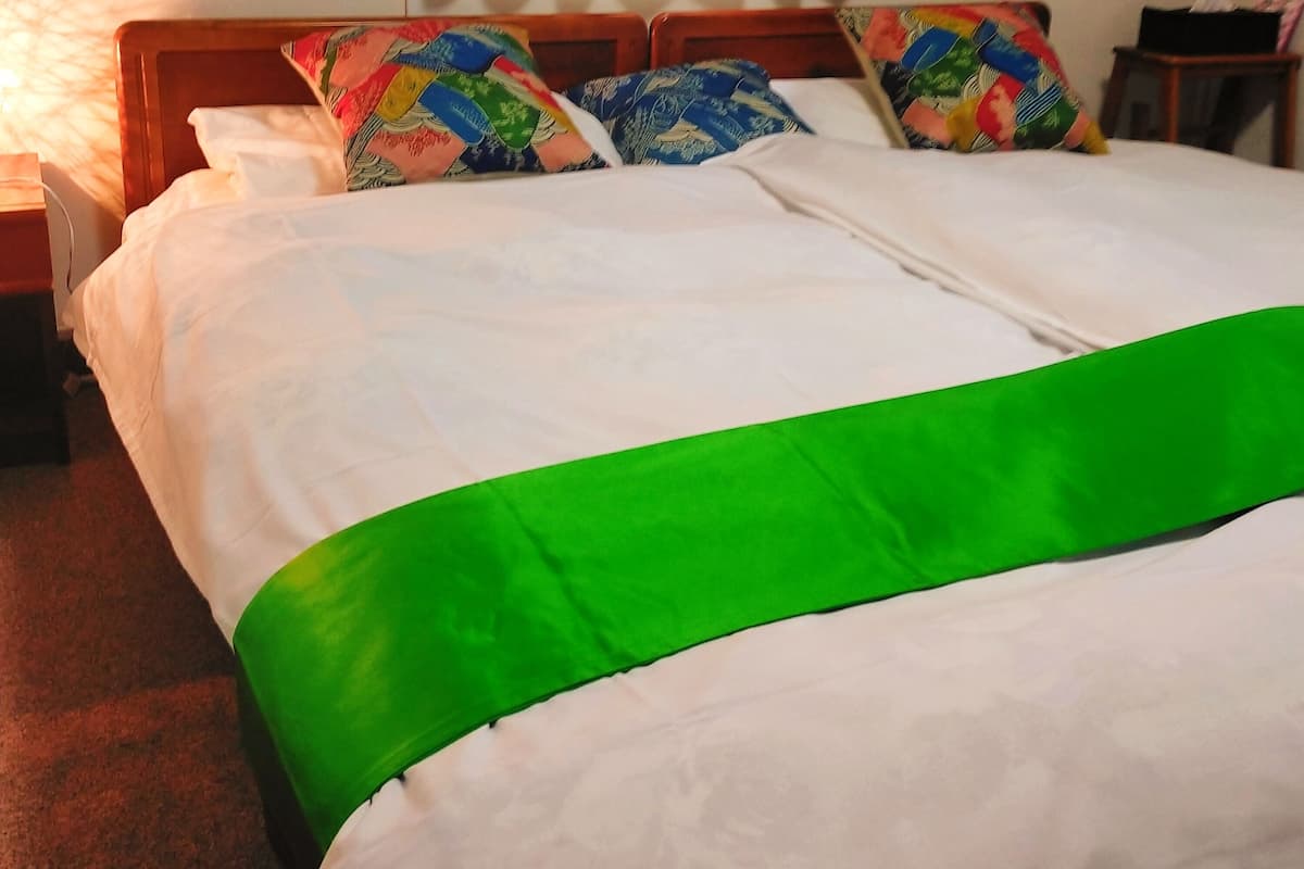 A hotel room with a large bed, two pillows, a nightstand, and a lamp.