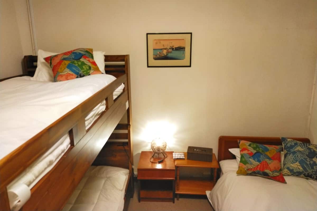 A room with two beds, a small wooden nightstand with a lamp, a framed picture on the wall, and a small table with a globe and a box.