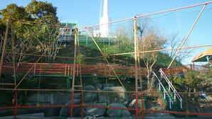 A construction site with scaffolding, a white tower, and a green-roofed building. - Seaside Hostel LightHouse (Onomichi)