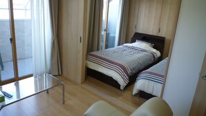 A bedroom with a bed, a chair, and a sliding glass door leading to a balcony. - Seaside Hostel LightHouse (Onomichi)