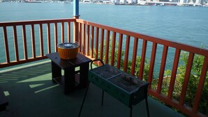 A balcony with a view of a waterfront cityscape, a grill, and a metal chair. - Seaside Hostel LightHouse (Onomichi)