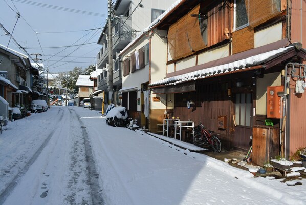 A narrow street lined with traditional wooden buildings, some with snow on the ground and roofs. - Guesthouse Bon (Kyoto)