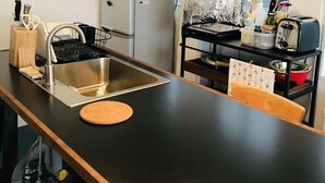 A compact kitchen with a sink, a microwave, a refrigerator, a toaster, and a window with curtains. - Hostel Chapter Two Tokyo (Tokyo)