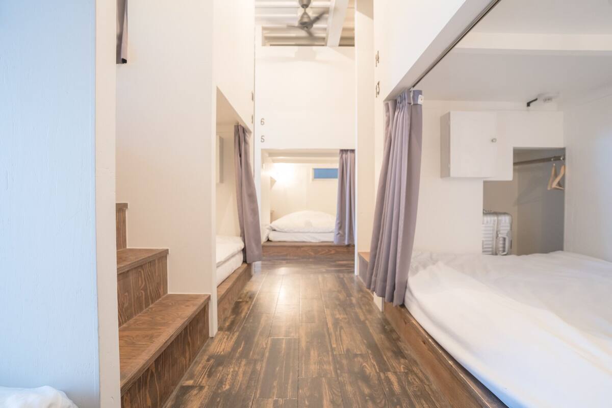 Un pasillo estrecho con piso de madera que conduce a una habitación con literas.