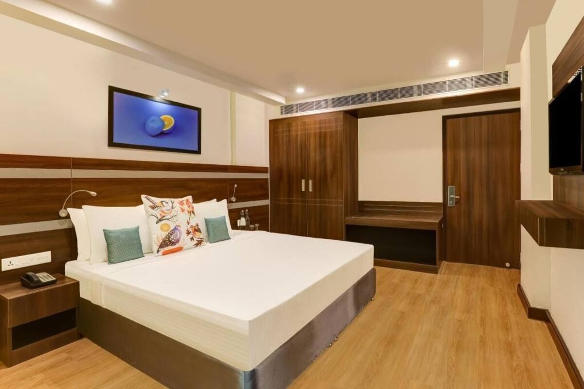 Une chambre à coucher comprenant un lit, une table de chevet, une armoire et un téléviseur fixé au mur.