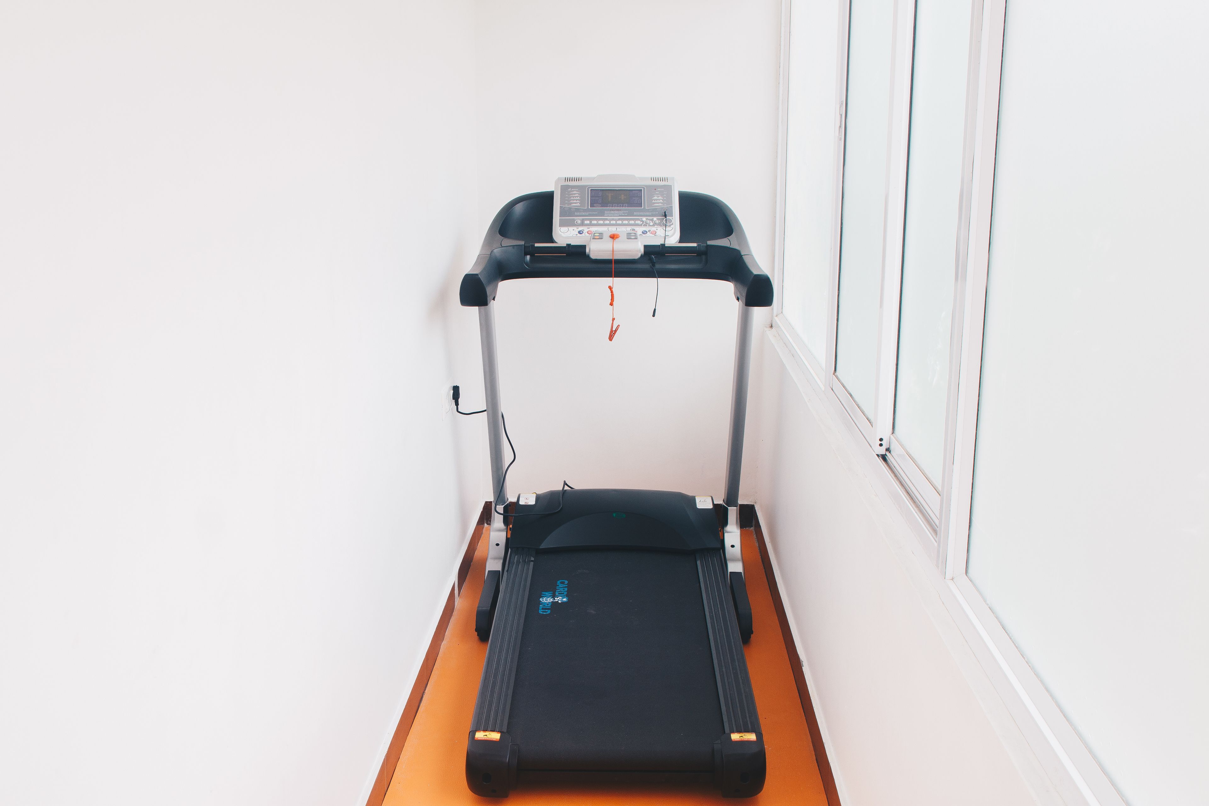 A treadmill in a room with white walls and a wooden floor.