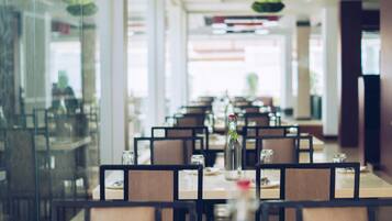 Un restaurante con mesas dispuestas para comer, sillas y una botella sobre la mesa.