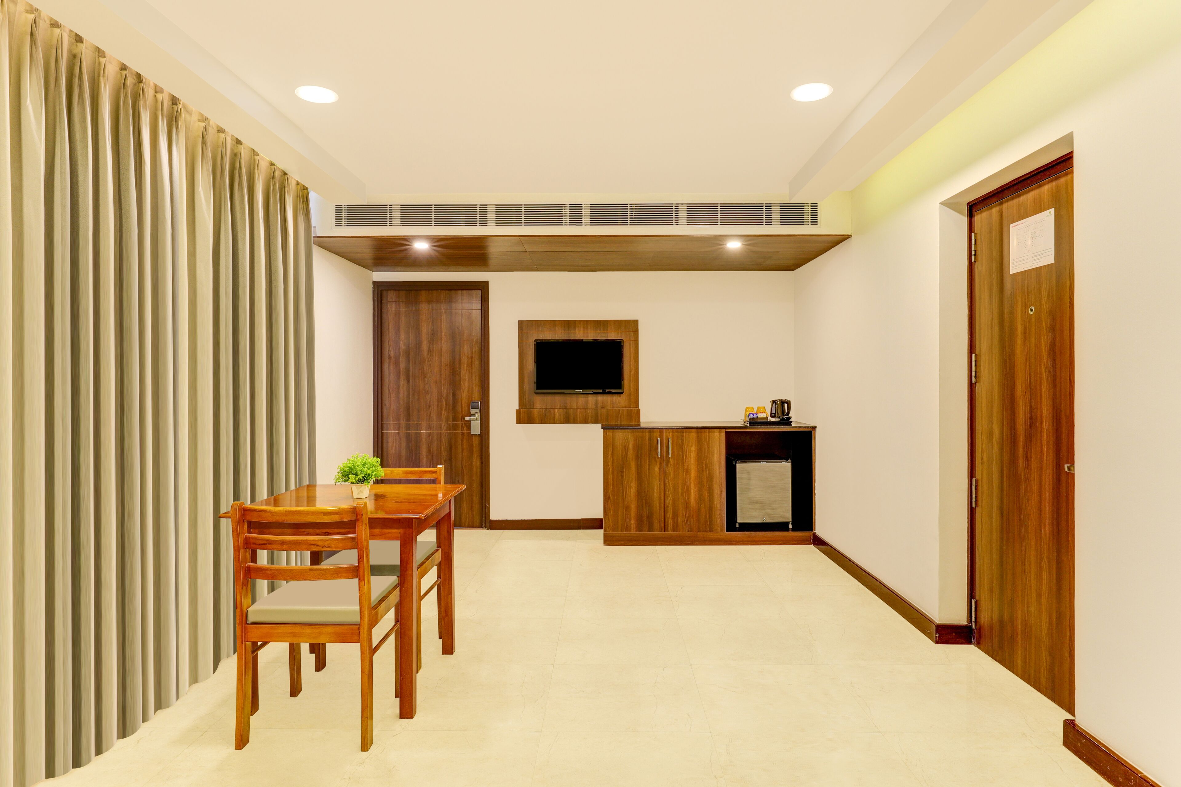 Una cocina compacta con comedor, armarios de madera, televisor integrado y un refrigerador pequeño.