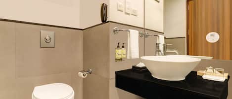 A modern bathroom with a white toilet, a large white sink, and a black countertop.