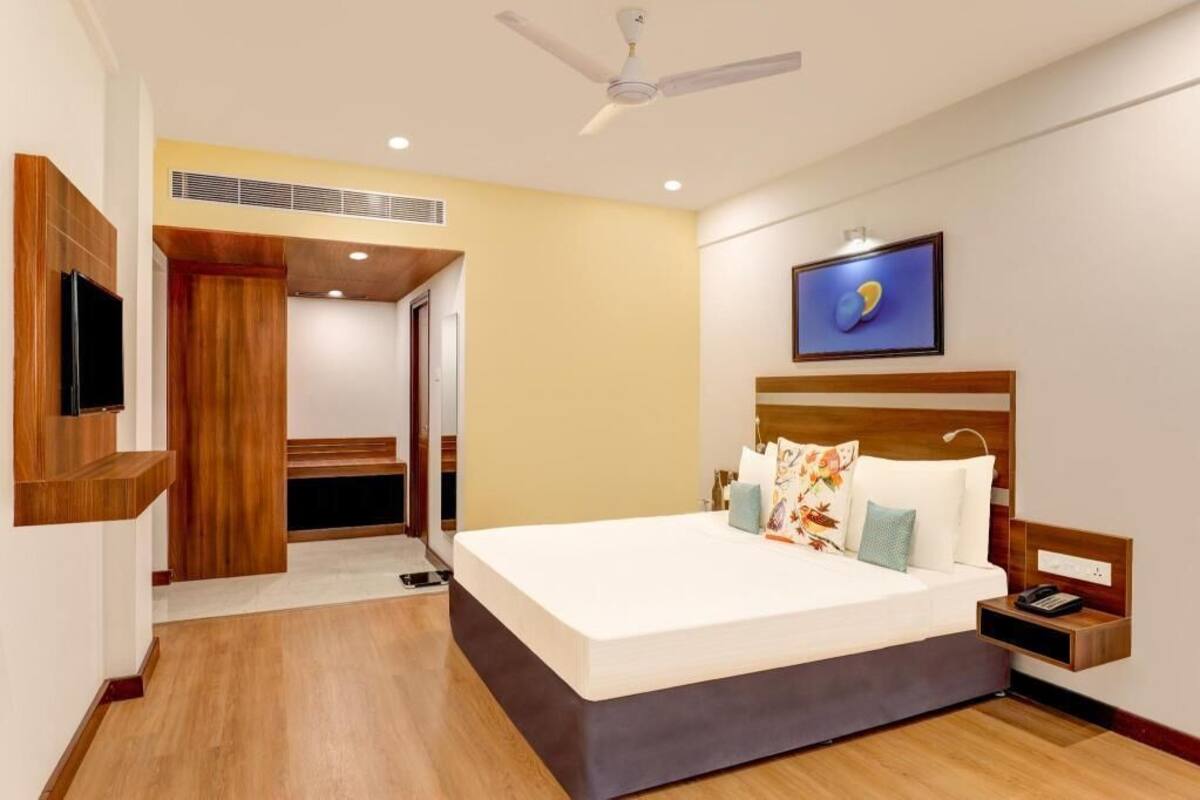 Une chambre d’hôtel moderne équipée d’un lit, d’une table de chevet, d’une télévision et d’un ventilateur de plafond.