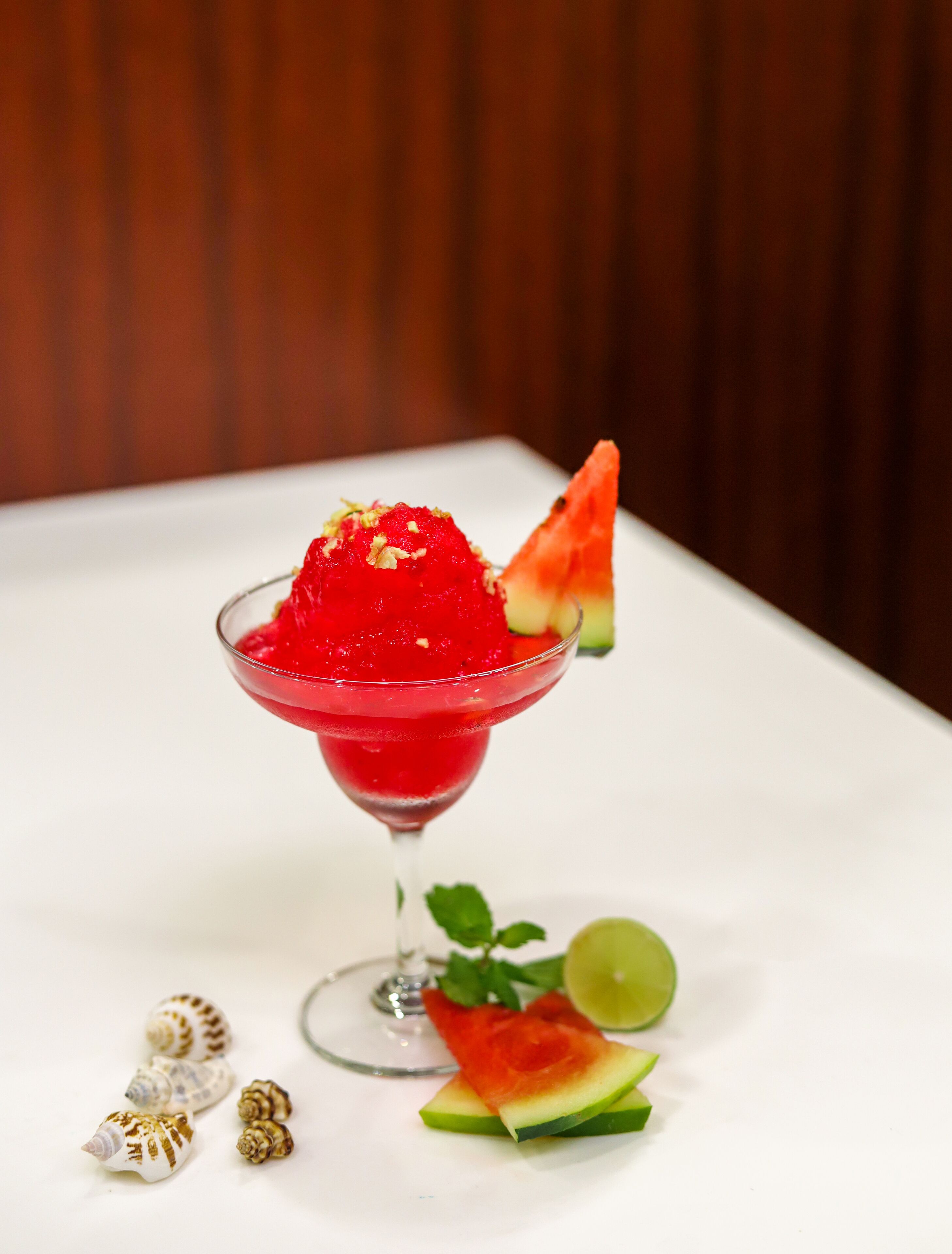 A dessert in a martini glass with watermelon and mint garnish.