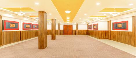 A spacious hall with wooden paneling, a herringbone-patterned floor, and framed artwork on the walls.