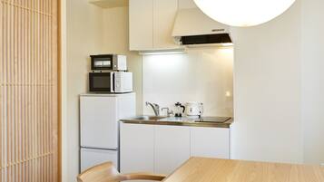 A compact kitchen with a microwave, refrigerator, sink, and kettle.