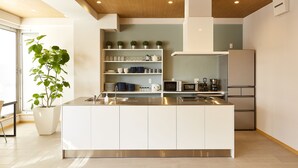 A modern kitchen with a central island, stainless steel appliances, and a potted plant.