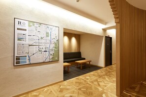 A lobby with a map, a sofa, and a wooden floor pattern. - R Star Hostel Kyoto Japan (Kyoto)