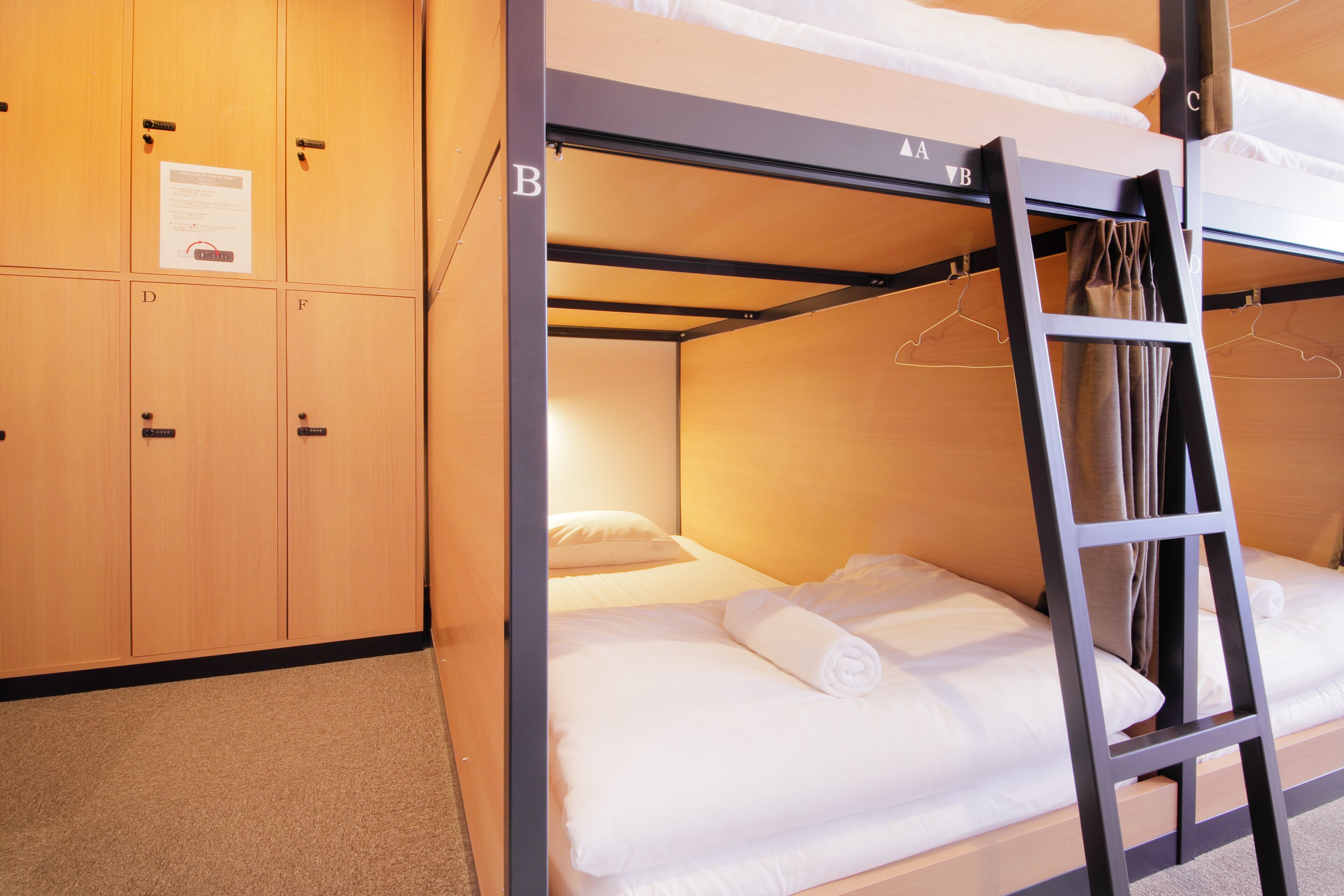 Uma cama beliche com escada, guarda-roupa de madeira e um cabideiro.