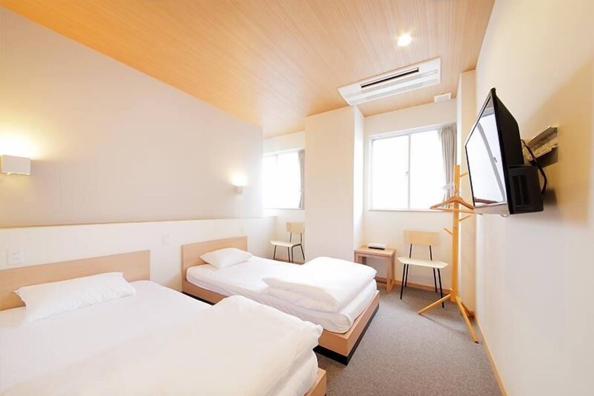 Une chambre d’hôtel avec deux lits, une télévision, une petite table et une chaise.