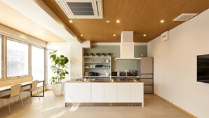 A modern kitchen with a central island, built-in appliances, and a dining area with chairs.