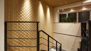 A modern interior with a wooden textured wall, a staircase with black railings, and a window with blinds.