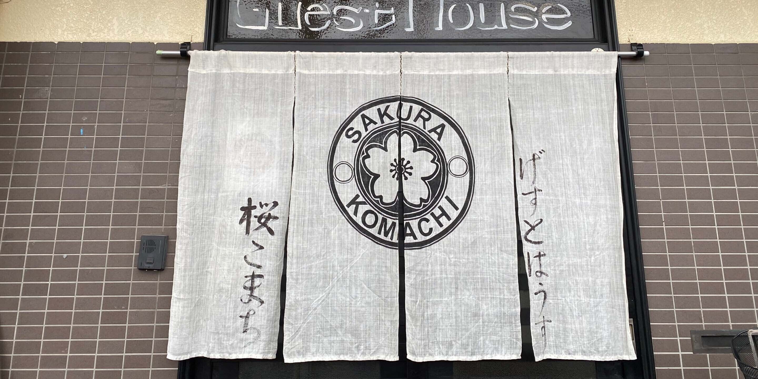 Un restaurante con un letrero que dice 'Sakura Komachi' y una cortina con caracteres japoneses.