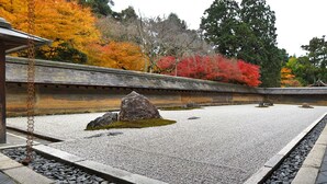 Un jardín japonés tradicional con un sendero de piedra, un jardín de rocas y una estructura de madera.